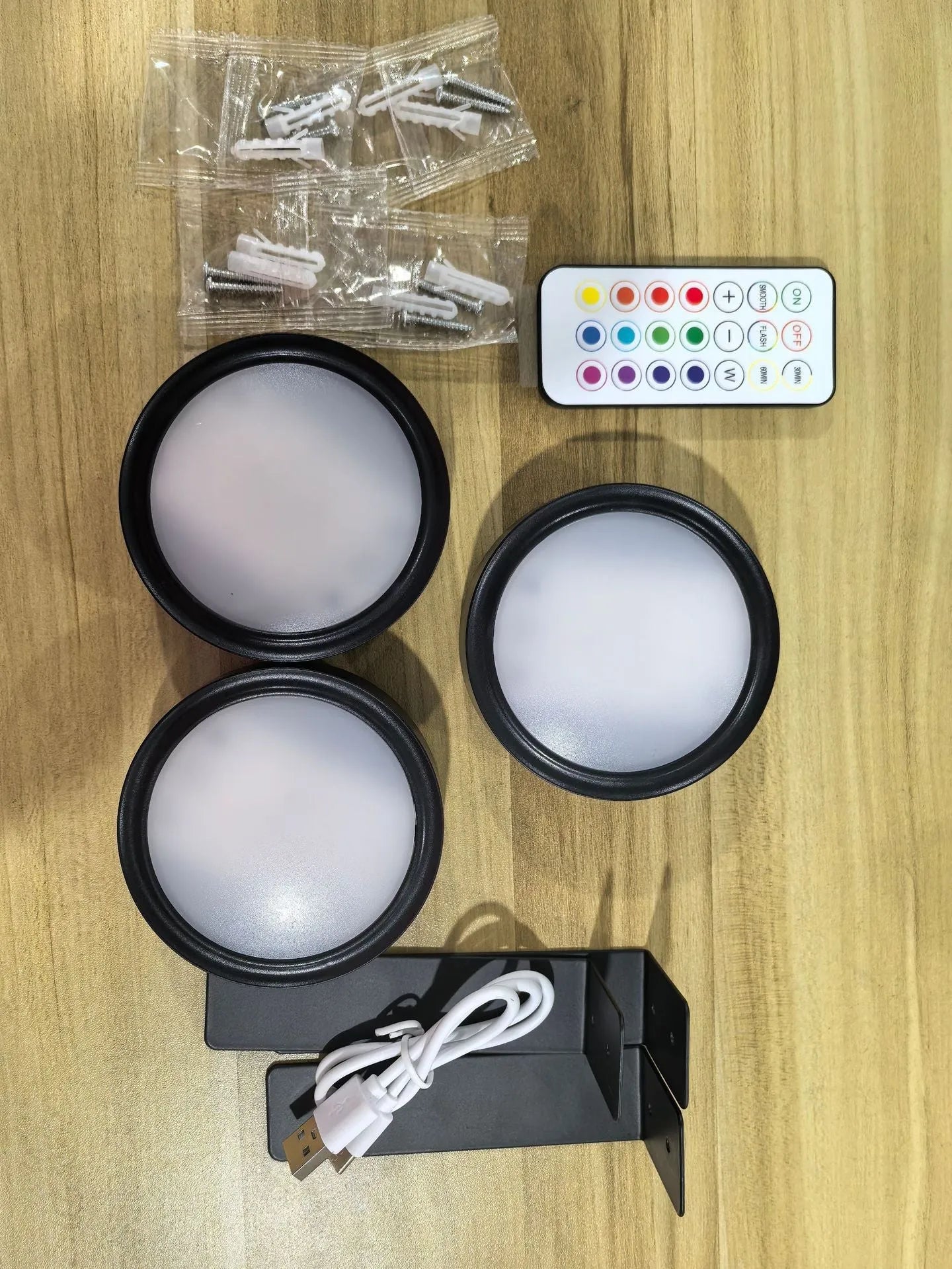 Black magnetic wireless LED lamp with remote control mounted next to a painting on a wall.