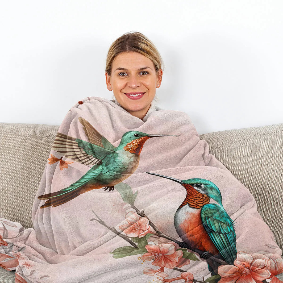 Pink hummingbird floral fleece throw blanket made of soft flannel velvet, folded on a sofa