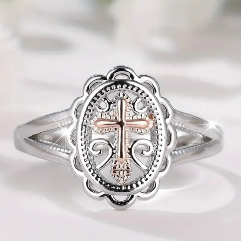 Silver women's ring with detailed cross and lace pattern, shown on a finger.