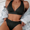 Women's pink halter strap bikini top and matching shorts on a neutral background.