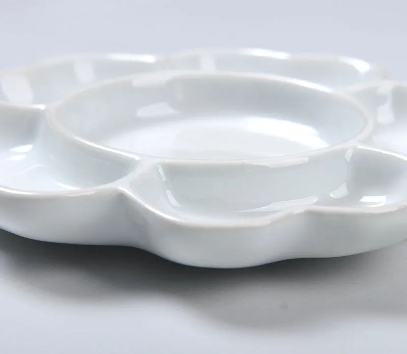 White hand-made ceramic plum blossom shaped artist palette for paint mixing.