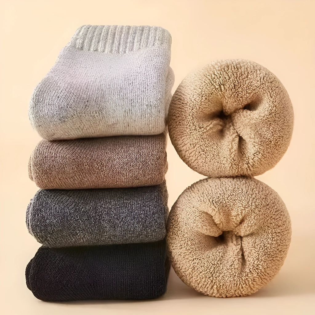 Pair of thick grey merino wool winter socks showing reinforced padded midsole and seamless toe.