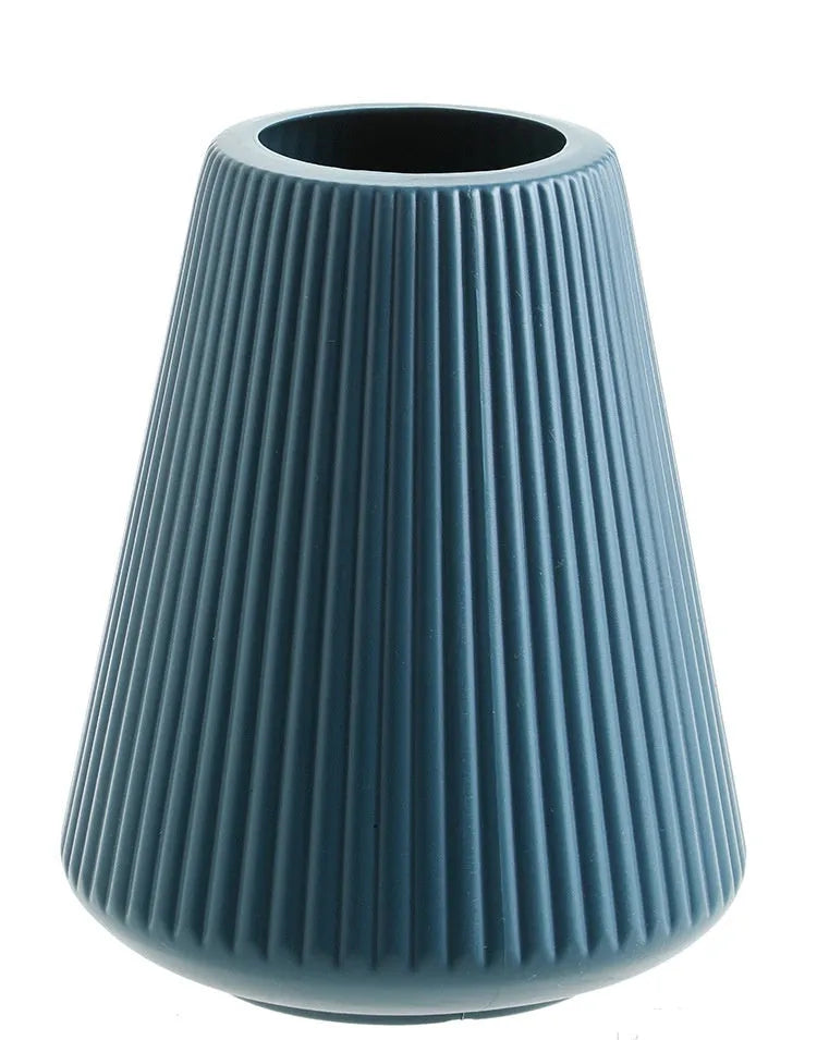 Colourful melamine plastic flower vase in blue, green, pink, or white on a desk.