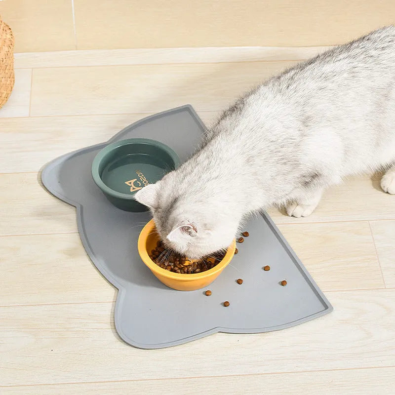 Blue silicone cat head-shaped pet feeding mat on a wooden floor