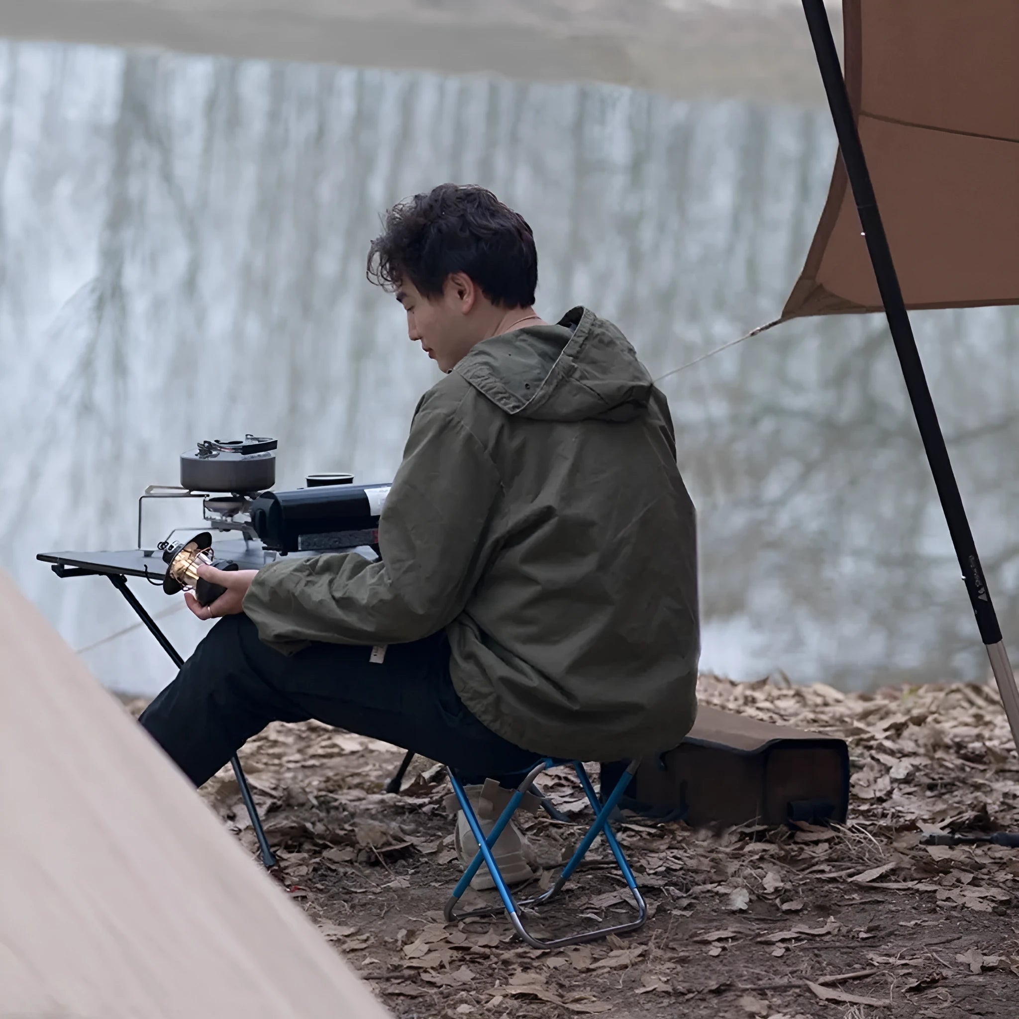 Black folding camp stool with aluminium alloy frame, shown in folded and open positions.