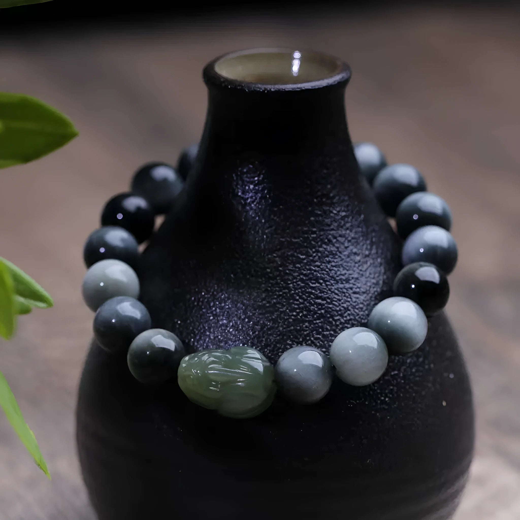 Black 10mm Eagle Eye Stone bracelet with a natural Hetian Jade Pixiu charm showing a clear water pattern.