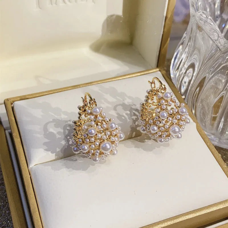 A pair of gold-coloured copper flower basket earrings with pearl inlay and small rice-shaped bead details.