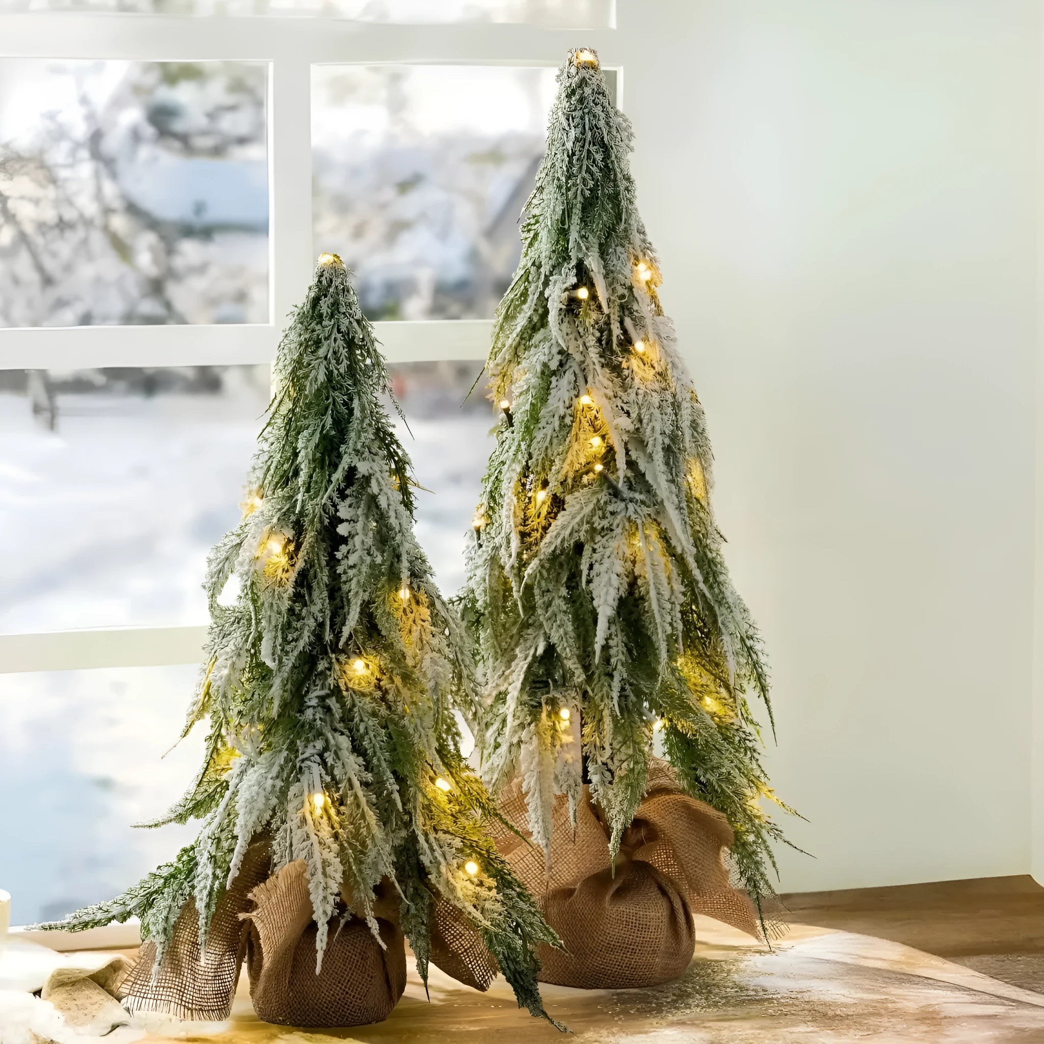 Small 24-inch plastic Christmas tree with LED lights and snow-covered branches on desktop