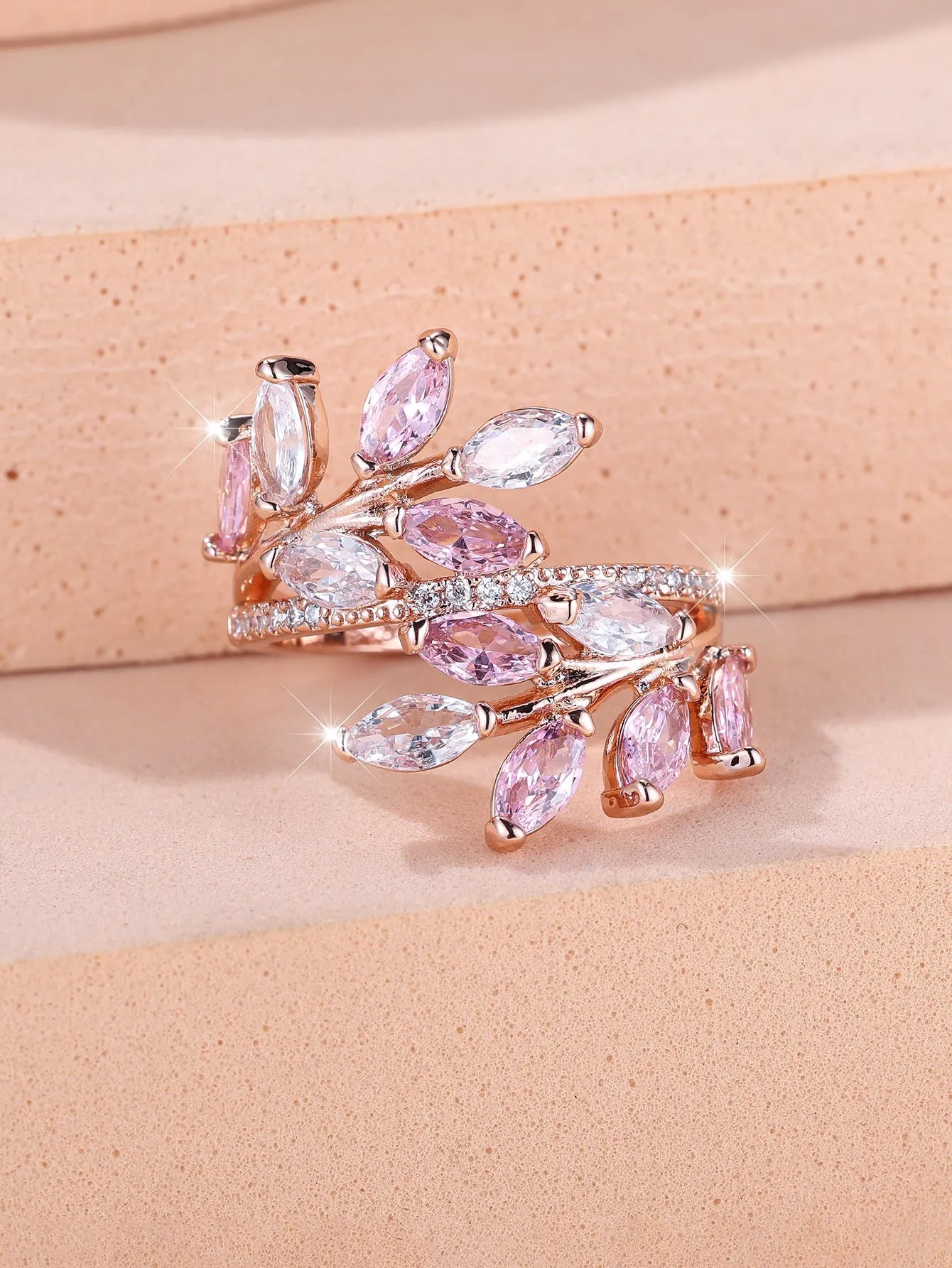 Adjustable copper leaf ring with a central zircon stone on a finger, showing rose gold and platinum colour options.