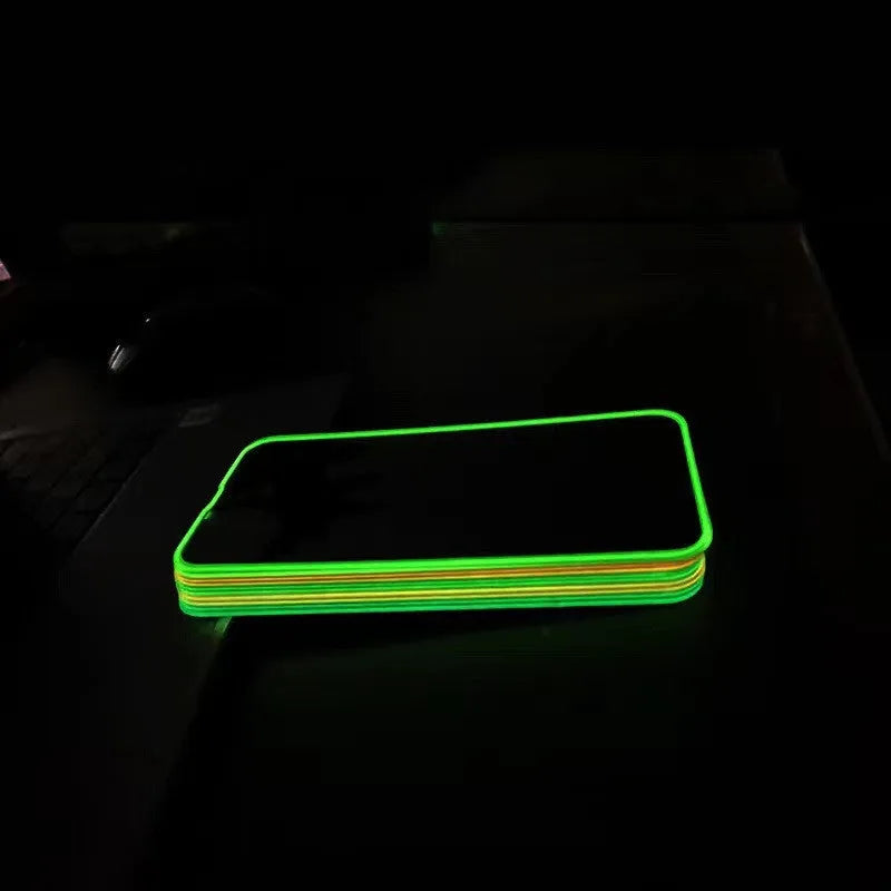 Fluorescent pink tempered glass screen protector glowing on an iPhone 13 in a dark room.