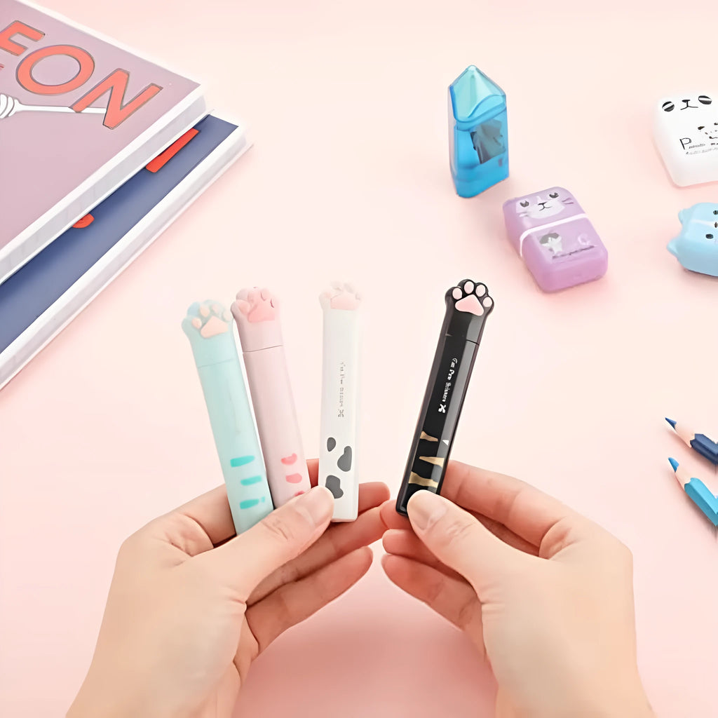 Set of four mini folding scissors with cat paw design in black, blue, pink, and white colours on a plain surface.