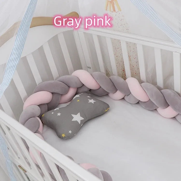 Close-up of a grey braid knot pillow cushion cot bumper fitted around white crib rails.
