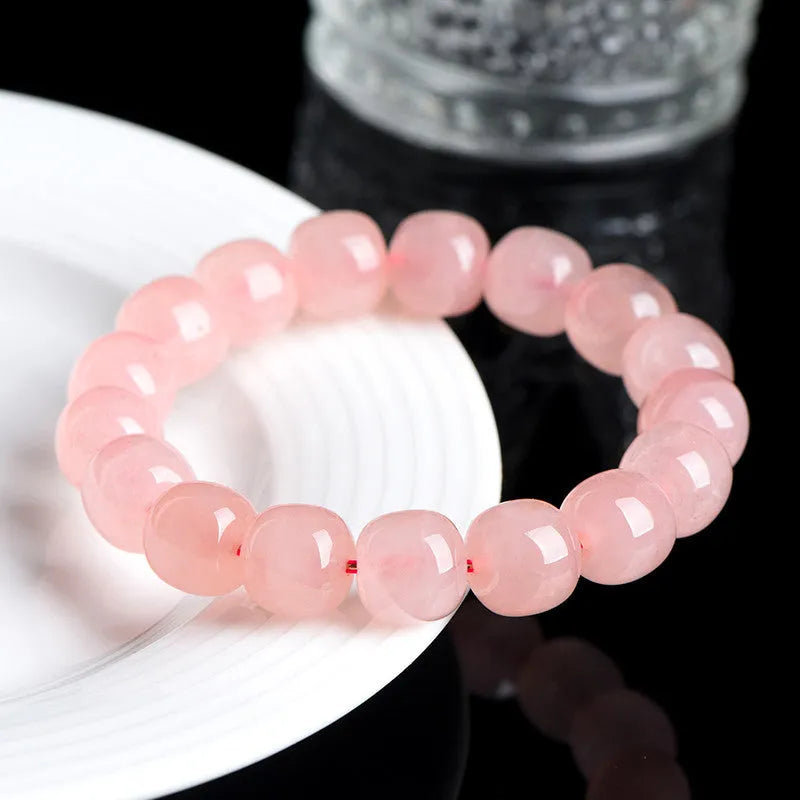 Close-up of a pink natural crystal bracelet with polished barrel-shaped beads measuring 8-10mm.
