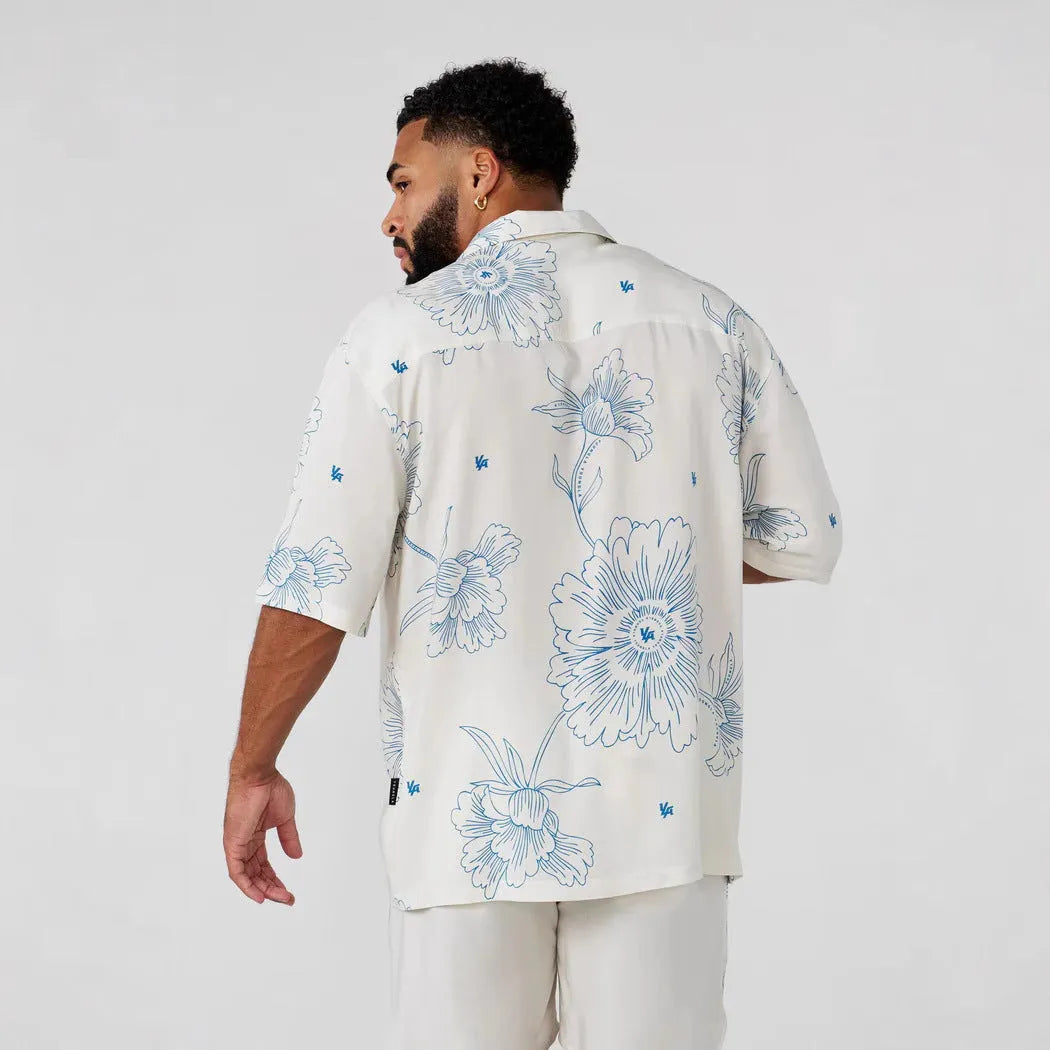 Men's loose-fit short sleeve top with floral print in light colour, laid flat.
