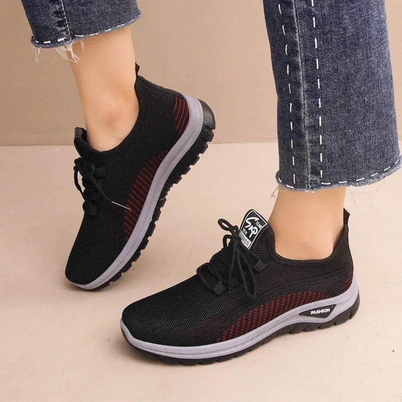 Women's black mesh sneakers with cross-strap detail and round toe on a rubber sole.