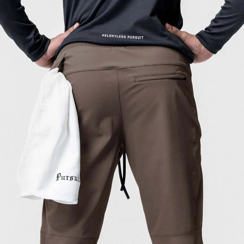Man wearing dark grey loose-fit ankle-tied fitness trousers made from quick-drying polyester.
