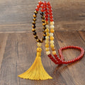 A long bohemian-style necklace with a geometric mixed gemstone pendant and a coloured tassel on a ball bead chain.
