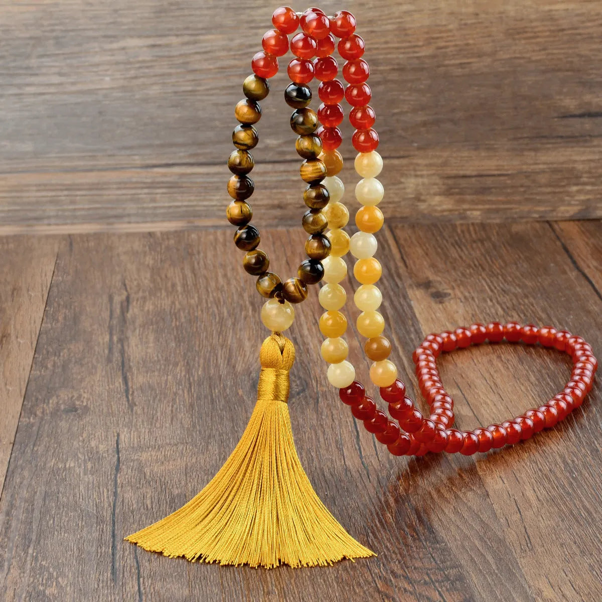 A long bohemian-style necklace with a geometric mixed gemstone pendant and a coloured tassel on a ball bead chain.