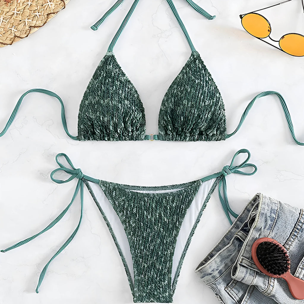 Green backless women's bikini with halter neck strap lying flat.