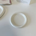 White ceramic plate with cartoon bear doodle design, shown next to round toot design plate, both microwave safe.