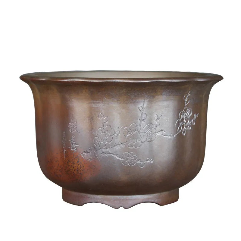 Antique carved ceramic flower pot with wood burning finish on a wooden table.