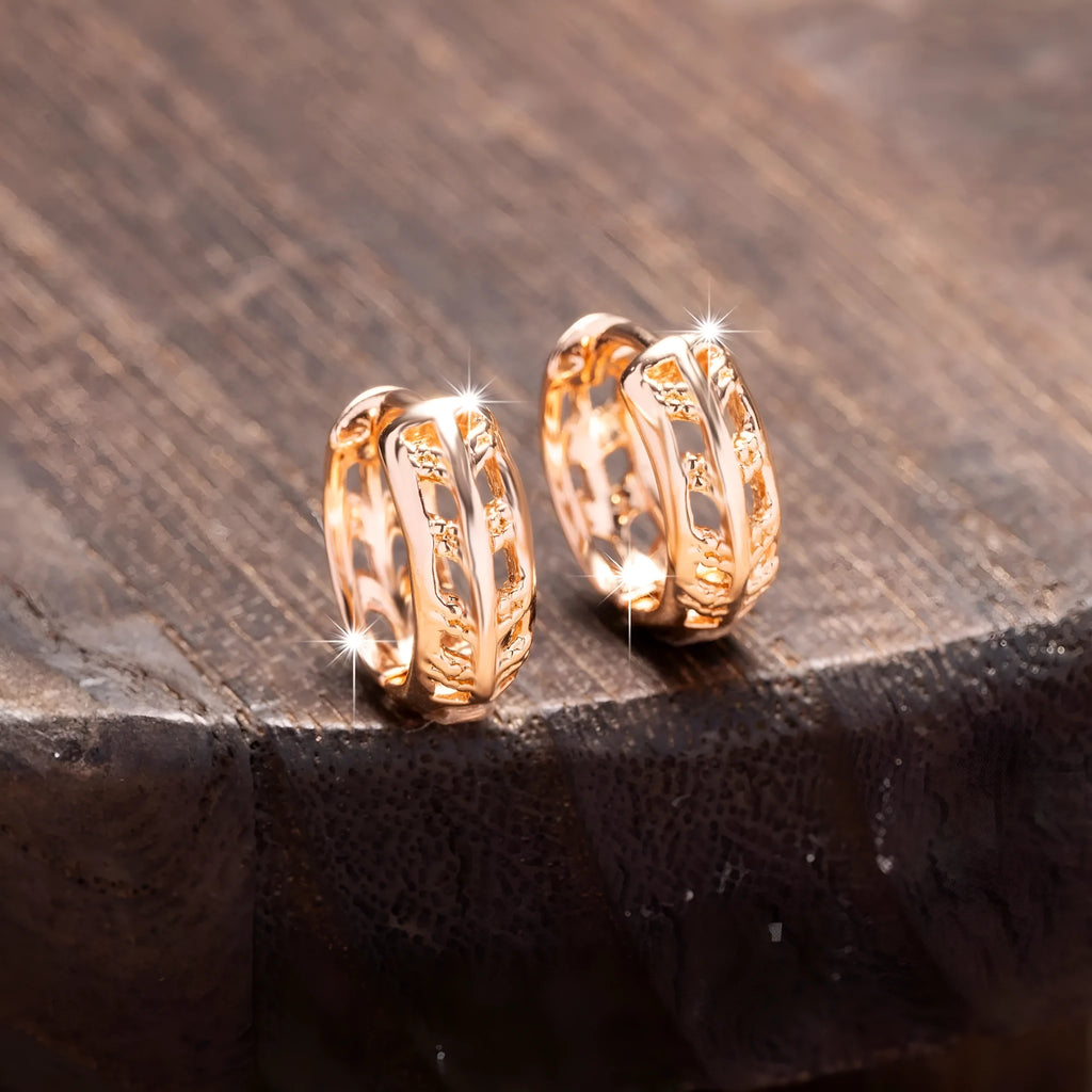 Small copper earrings with hollowed-out leaf and heart shapes in a rose gold colour.