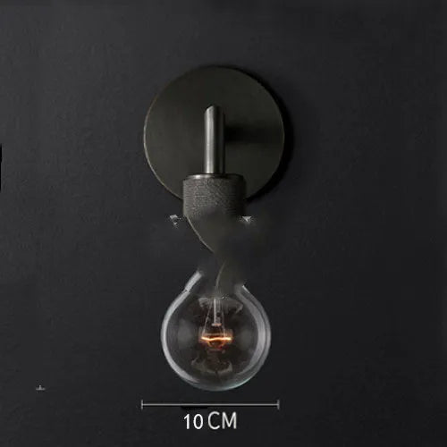Gold bronze or black wall lamp with triangular transparent glass shade and wrought iron frame for bedside or hallway use