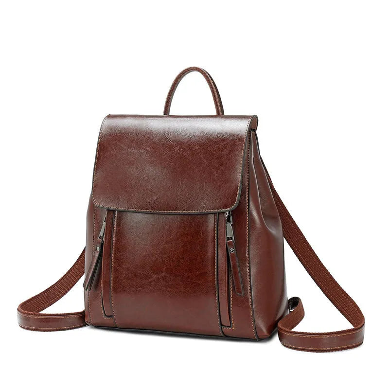 Brown oil-waxed cowhide leather women's backpack with flap closure, showing internal document pocket and stitching detail.
