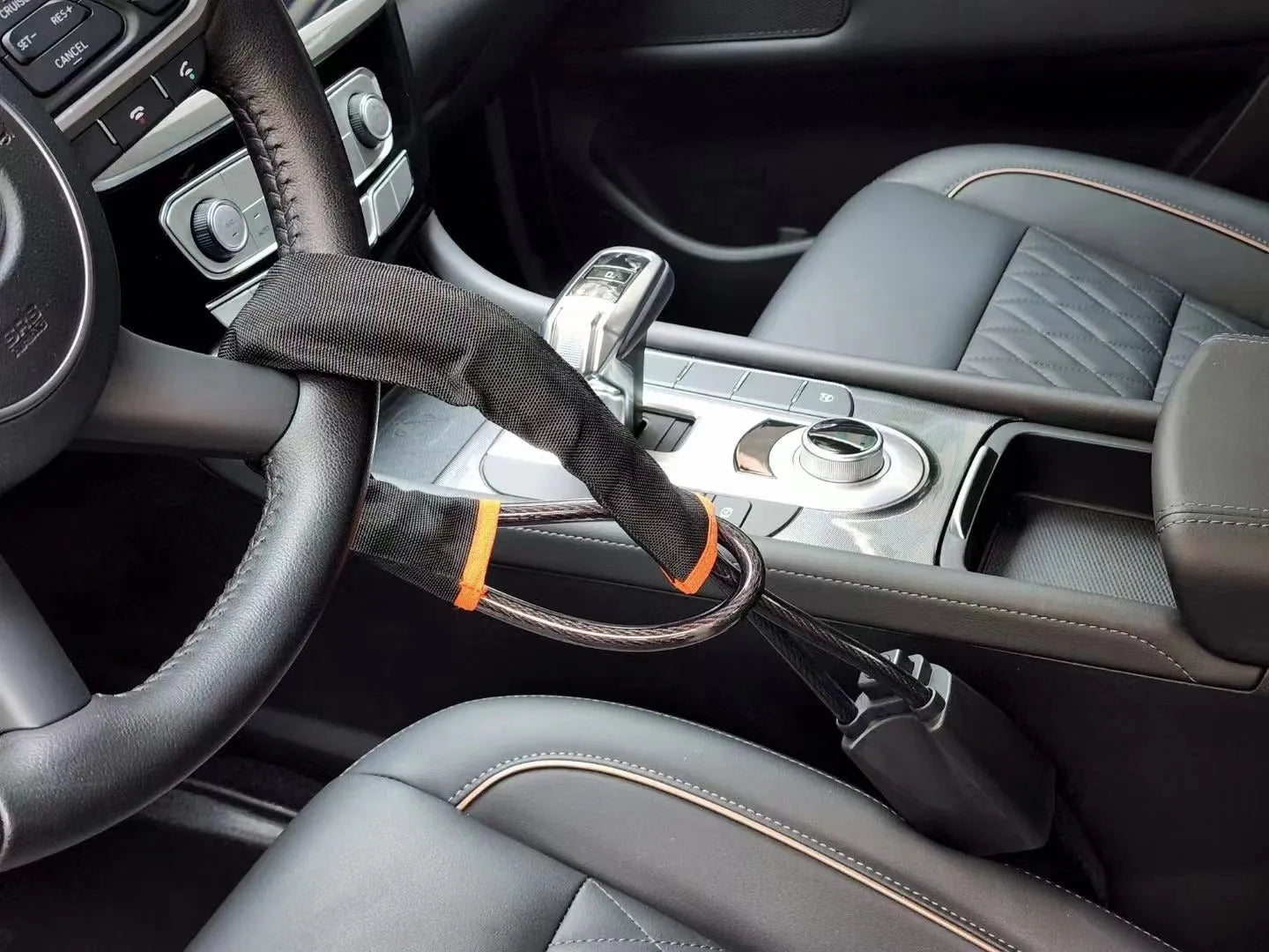 Red iron car steering wheel lock with wire rope for General Motors vehicles on a steering wheel.