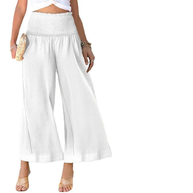 A woman wearing high-waist, pleated, straight-leg cropped trousers in a casual setting.