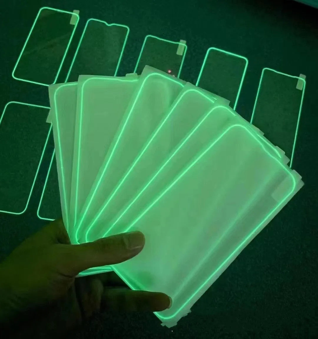 Fluorescent pink tempered glass screen protector glowing on an iPhone 13 in a dark room.