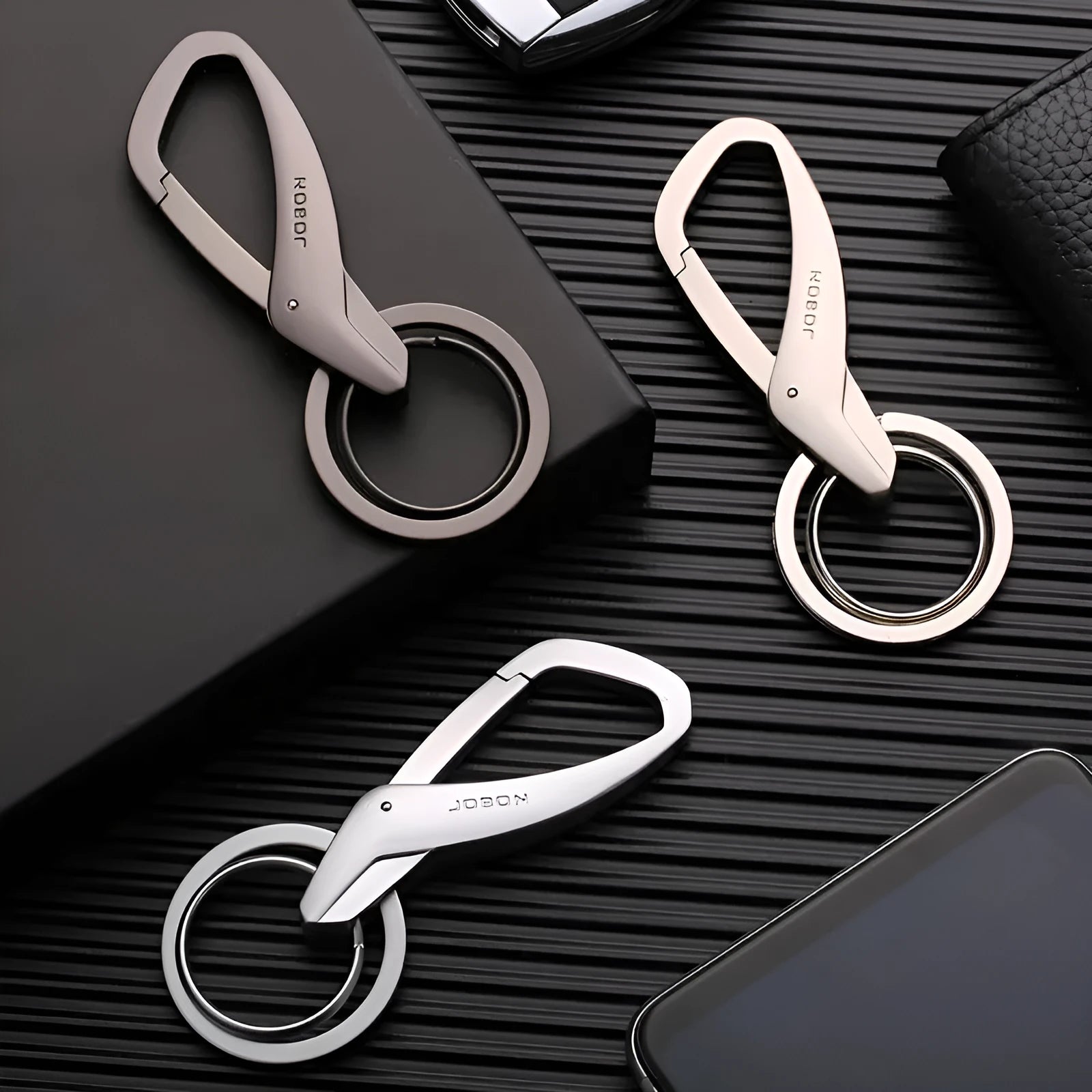 Black zinc alloy keychain with two split rings and a waist clip, shown next to a car key for scale.