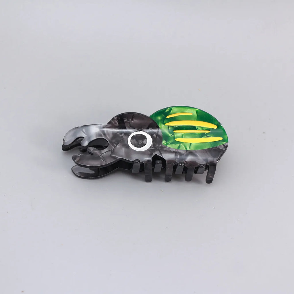 Handmade green beetle grip clip made from cellulose acetate on a desk with papers.