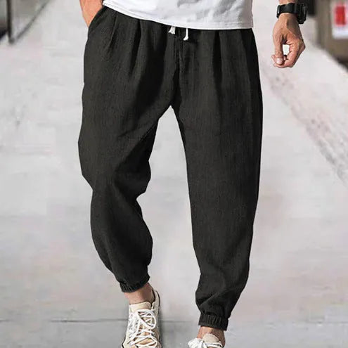 Men's loose-fit light green cotton casual trousers with a banded ankle cuff on a plain background.