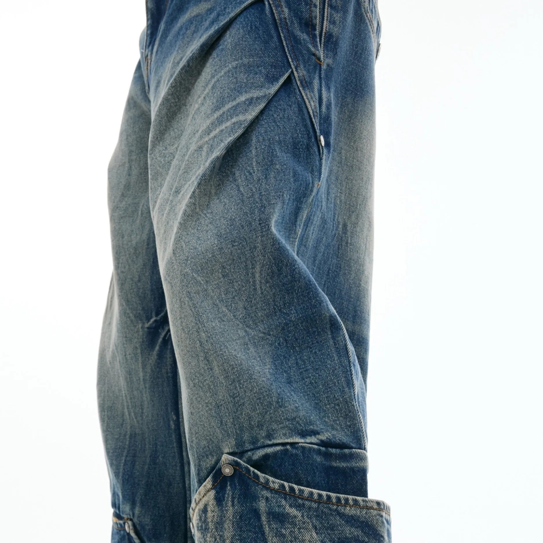 Man wearing verdant blue loose-fit curved knife jeans with a retro washed burst pattern, showing front and side view.