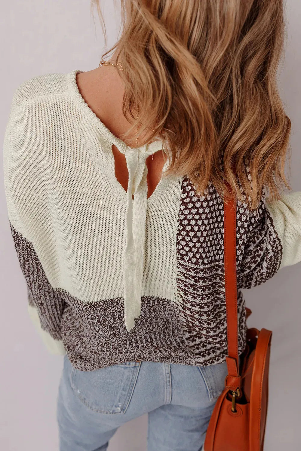 Dark khaki colour-block loose sweater with a back tie and drop shoulders on a hanger.