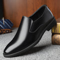 Men's black low-top slip-on leather shoes with a rubber sole and sewing line detailing.