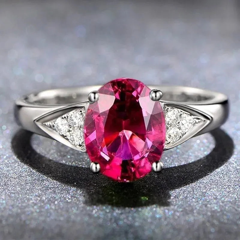 Close-up of a women's court-style silver-toned ring with an inlaid red natural zircon stone cut in a heart shape.