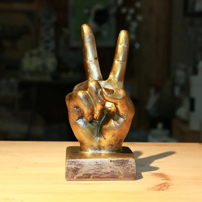 Resin hand gesture ornament in metallic finish on wooden surface