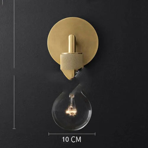 Gold bronze or black wall lamp with triangular transparent glass shade and wrought iron frame for bedside or hallway use