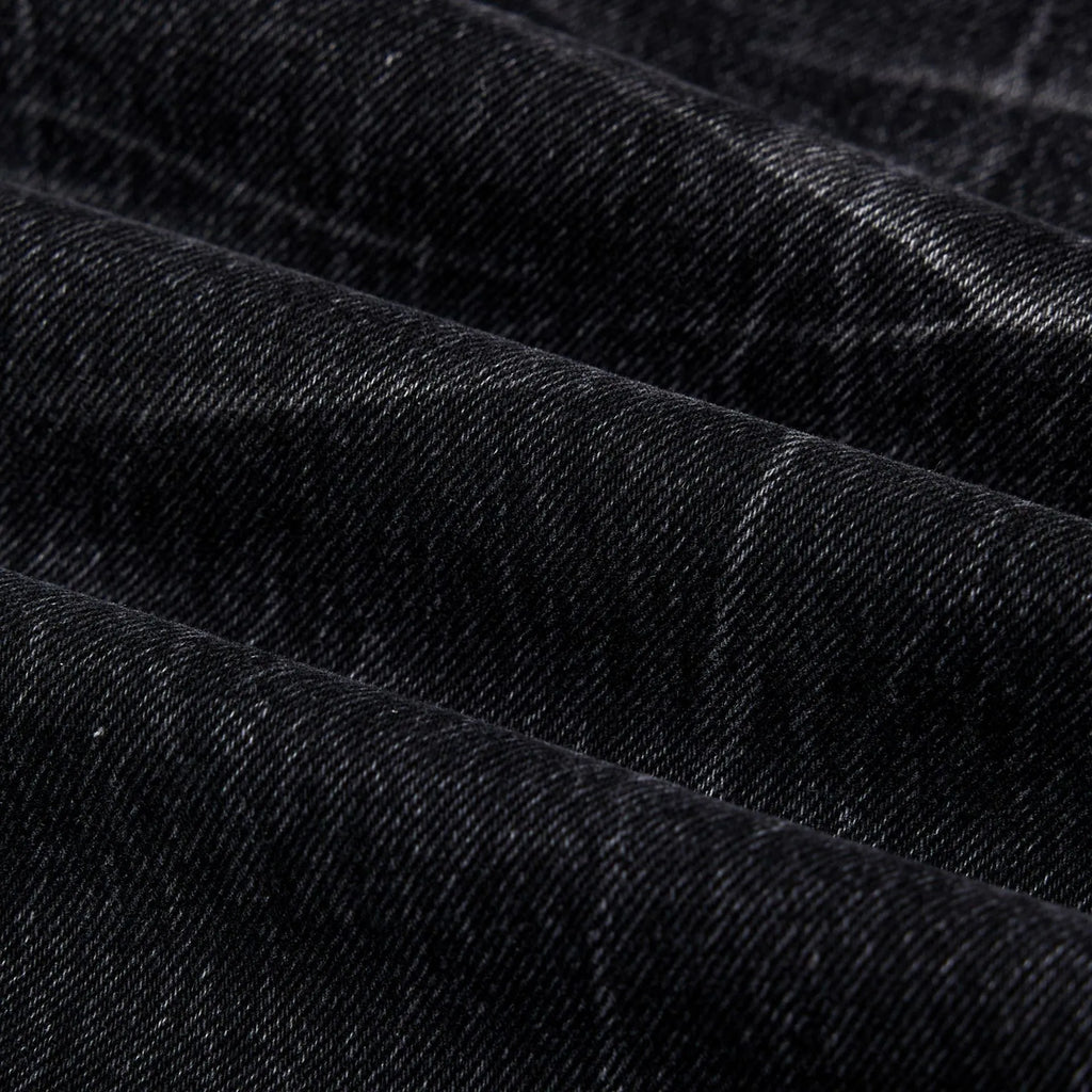 Men's black American washed straight leg jeans with old lightning crack detailing on a plain background
