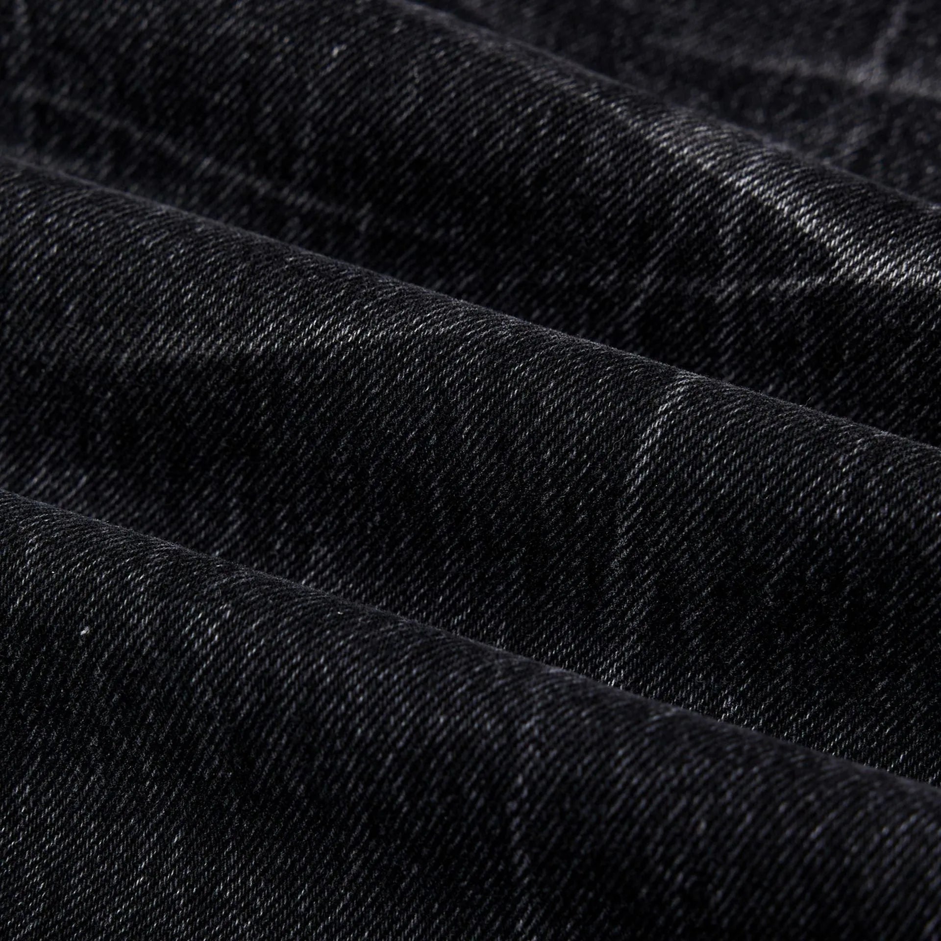 Men's black American washed straight leg jeans with old lightning crack detailing on a plain background