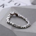 Handmade women's bracelet with an irregular silver square pendant on a wooden elastic band.