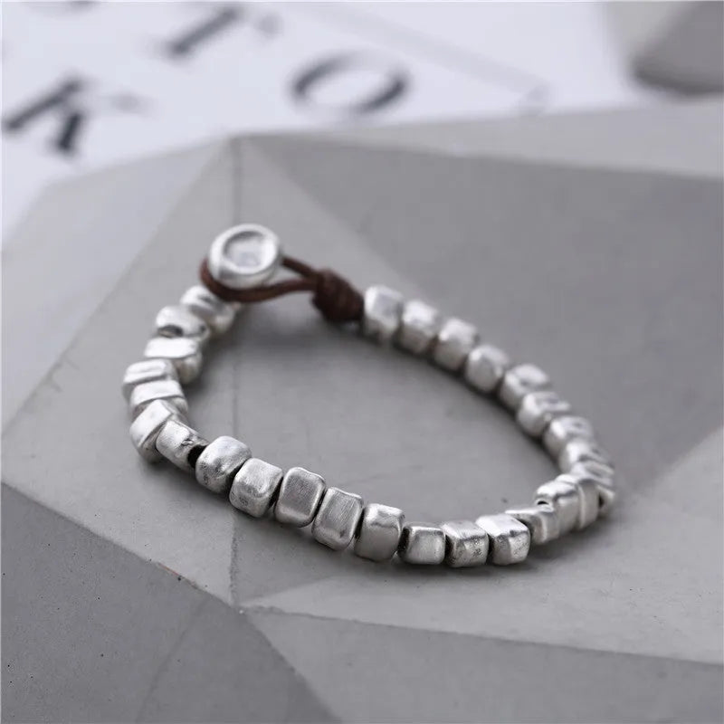 Handmade women's bracelet with an irregular silver square pendant on a wooden elastic band.
