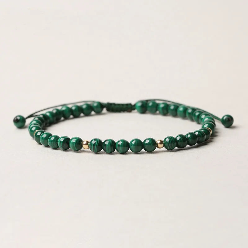 Natural green malachite crystal bracelet with golden balls on a woven hand strap.