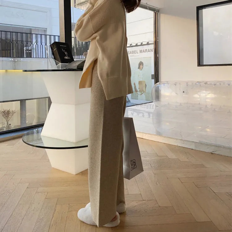 Women's high-waisted knitted wide-leg trousers in black, shown in a casual setting.
