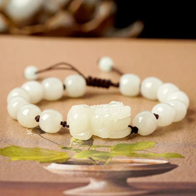 Close-up of a brown and black braided rope bracelet with a central Hetian jade bead on a wrist.