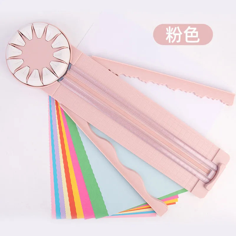 Pink and black 12-in-1 dotted line plastic rotary paper cutting machine on a craft table.