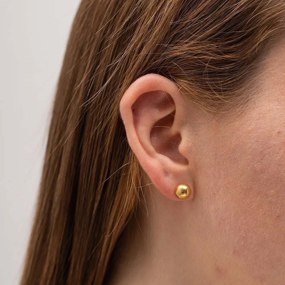 Simple gold-coloured stainless steel ball stud earrings in geometric design on a white background.