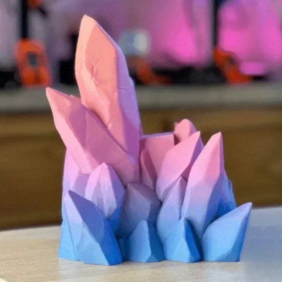 3D printing gamepad bracket in gradient colour, 20cm x 15cm x 10cm, on a desk beside a console